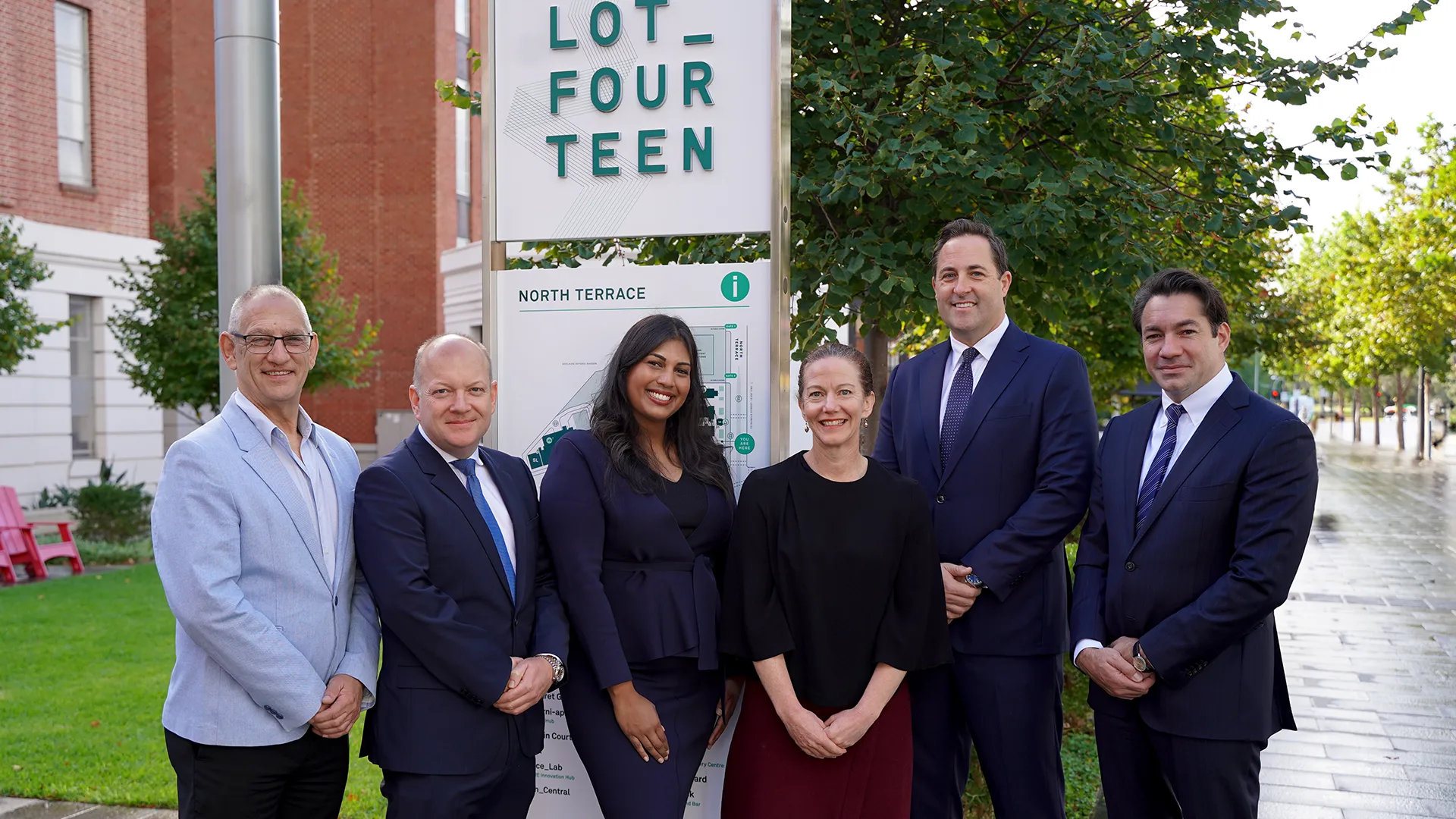 BennettLawers-LotFourteen-4 copy A group of professionals standing in front of the Lot Fourteen sign, smiling