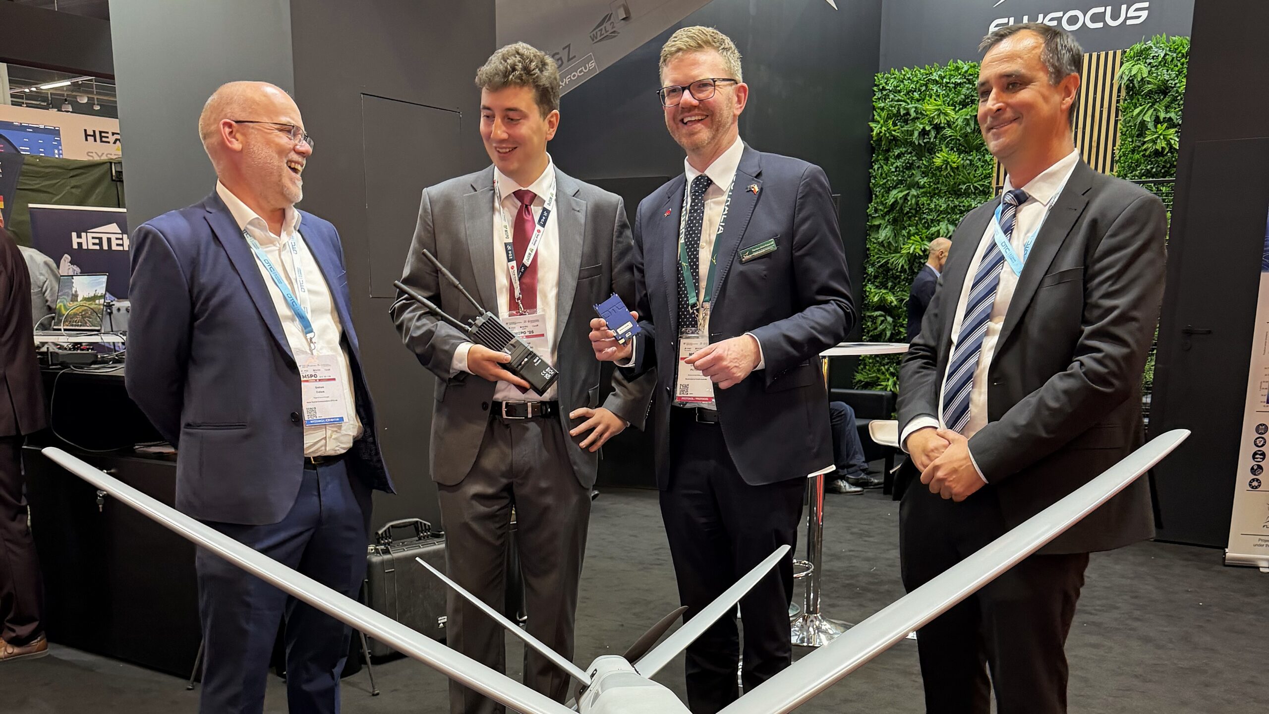 DTC and FlyFocus with Minister Chris Picton Four men in suits standing in front of a drone at a defence expo