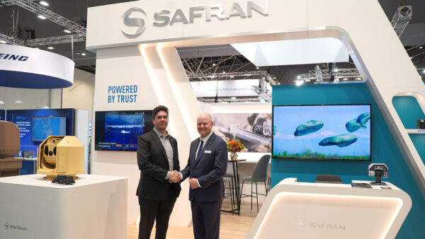 Two men in suits shaking hands at a defence event